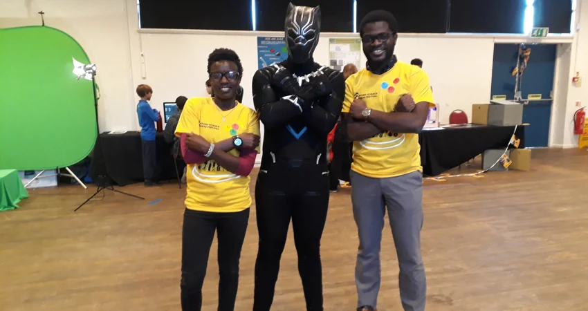 Two students stand either someone of person dressed as Marvel superhero Black Panther