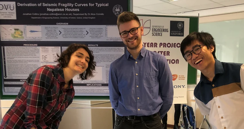 A photo of three people beside their poster display